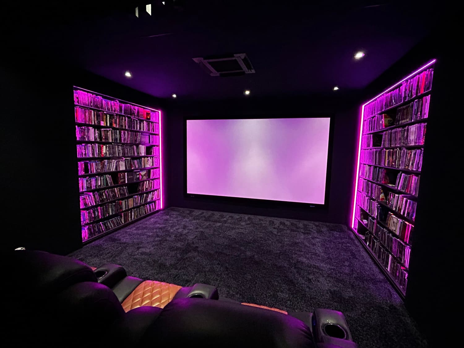 Dediziertes Heimkino mit Kinosesseln und RGB-beleuchteten Medienregalen