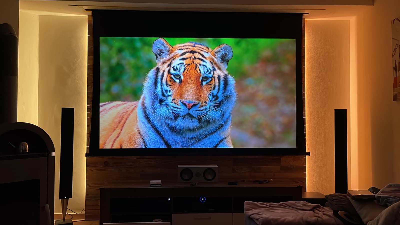 Wohnzimmerkino mit großer Rolloleinwand und warmem Ambientelicht